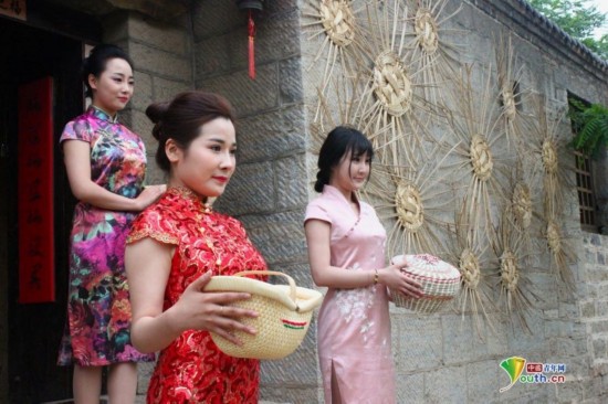 在上九山景区柳编景点，身着旗袍的美女正在展示柳编产品