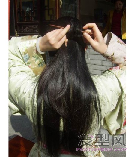 6、这时右手把簪子的尖转回来，从靠近右手这端挑一些紧挨头皮的头发，然后向左边插过去