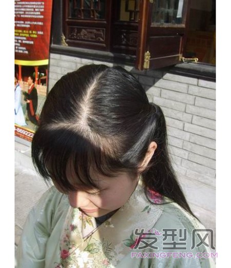 2、先把左边（右边也可以）的辫子从橡皮筋处握住，扭一下再往前耸，让耳鬓的头发蓬松而略微耸起，用黑色钢夹固定住橡皮筋处的头发，以便保持前面耸起的状况