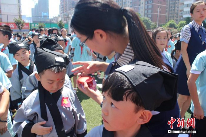 因为“痣”与“智”谐音,“朱砂点痣”意为开启智慧,希望学生在日后的学习中能目明心亮、一点就通。图为老师为新生点朱砂痣。