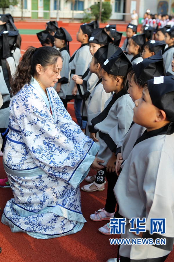 老师在“开蒙礼”主题活动现场为学生端正衣冠