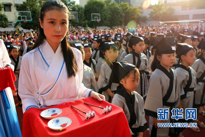 一名老师身着汉服准备为小学生朱砂启智。