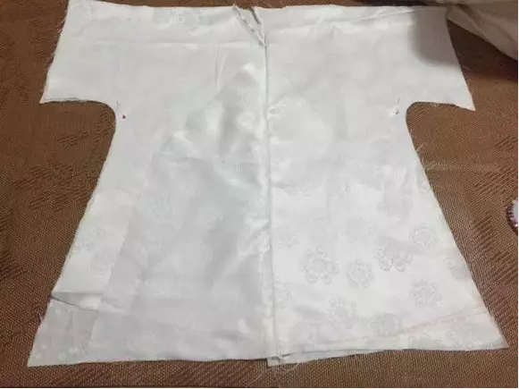 5、接衽车好之后，开始修剪下摆，因为打版时失误，下摆不是弧形。我画弧形用的是笨方法：先画直线，然后一点点修成弧形。用大头针将3层下摆固定住，开始裁剪。