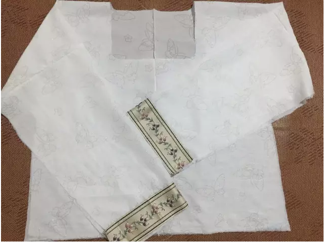 4、用包边条对领口进行包边，包边条买的现成的。其结构如下，就是一条绸带向内侧折叠好了，我们用的时候直接对折就行。