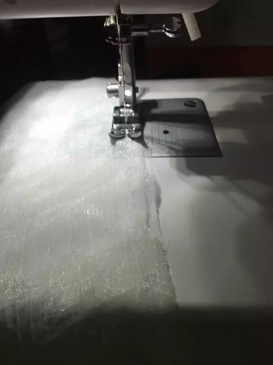 4、后中线缝好后，上衣就由两块布成了一体，然后把袖口卷边，缝好收起毛边。