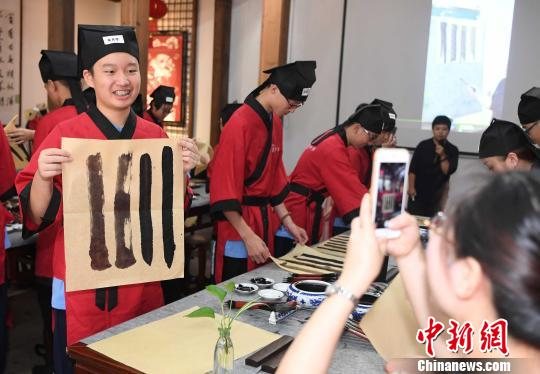 一名身着汉服的中学生喜悦展示首次学书画的“作品”。